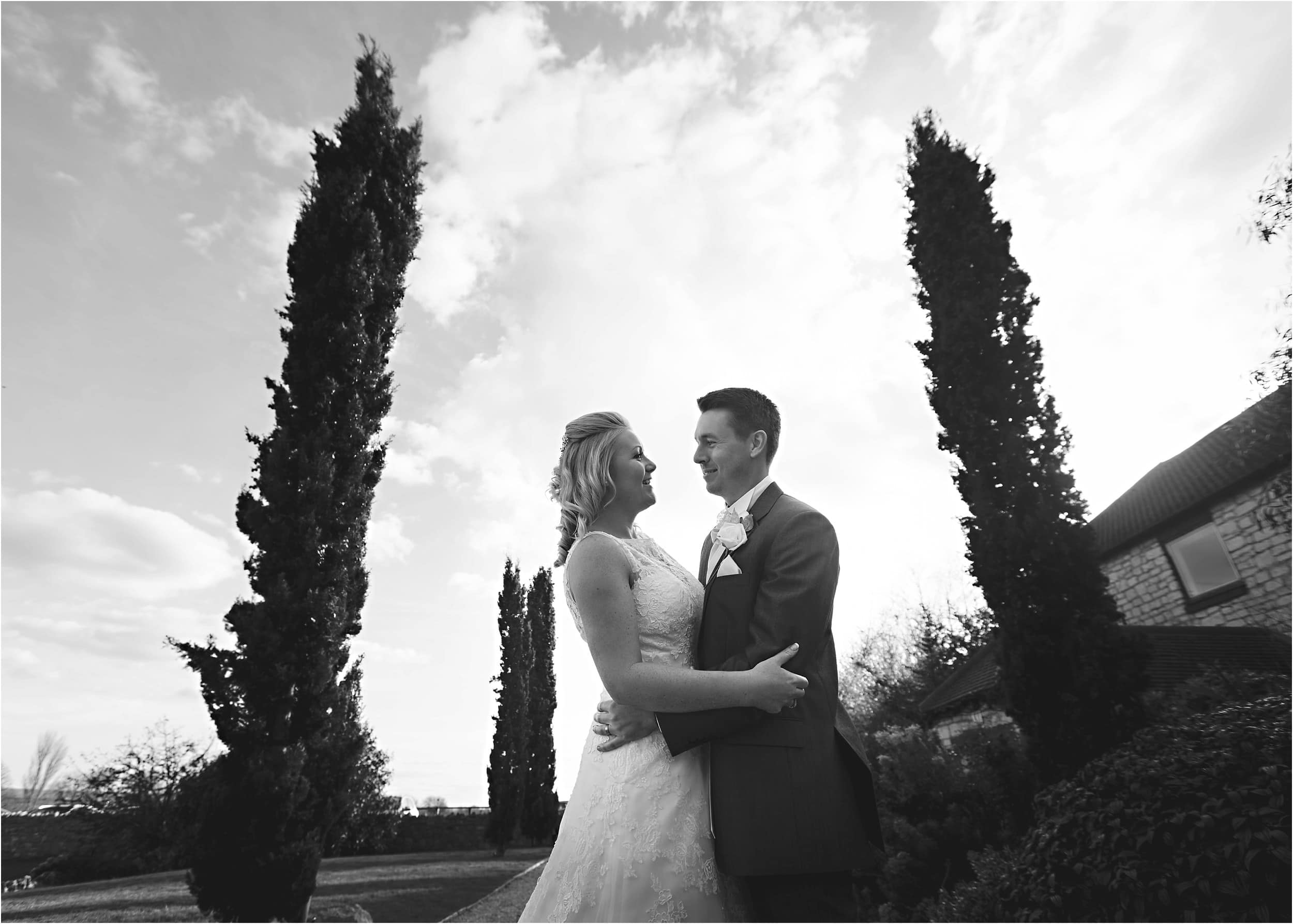bride and groom stood against tall trees