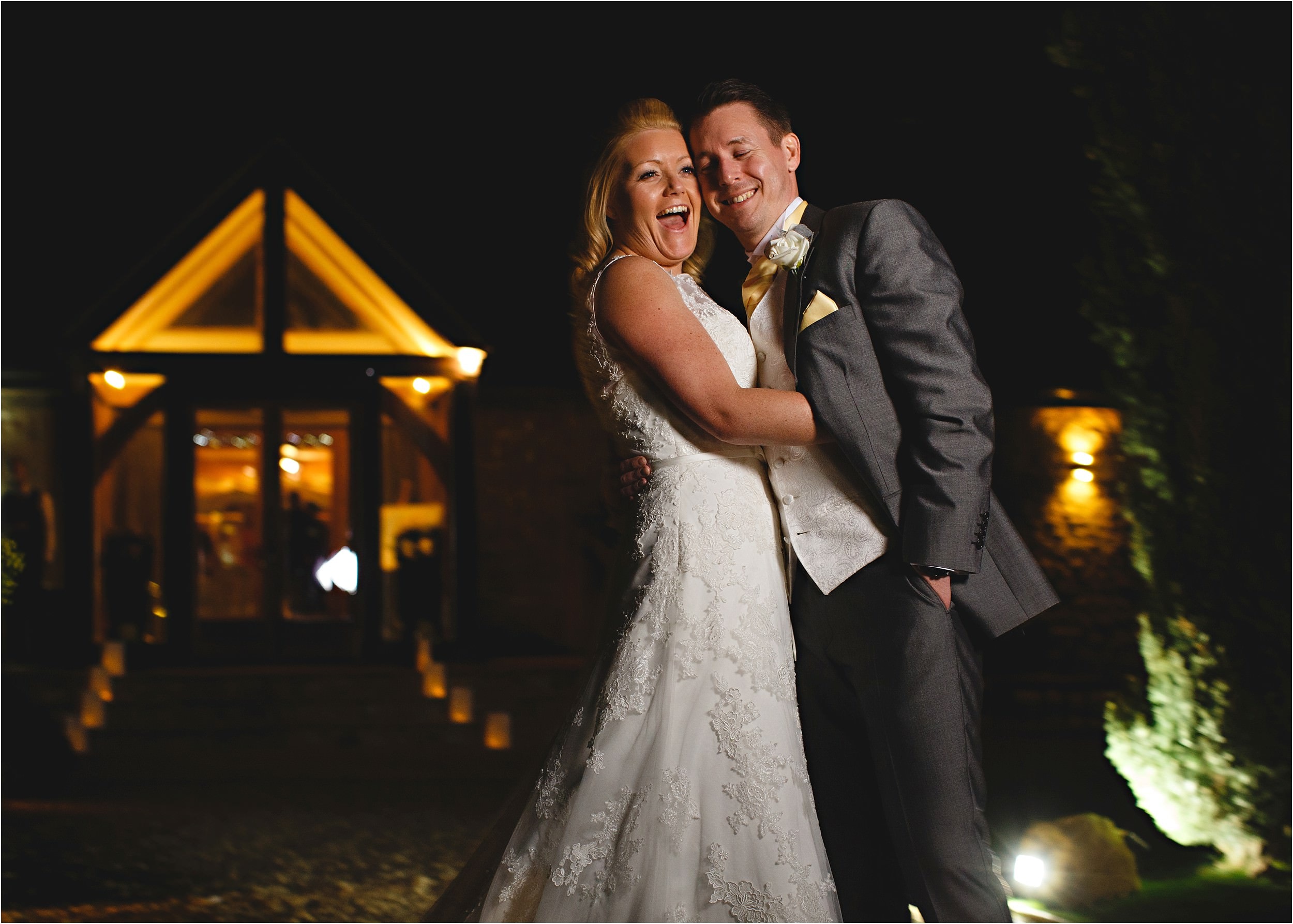 the bride and groom laughing at night time in front of Notley Thyme Barns