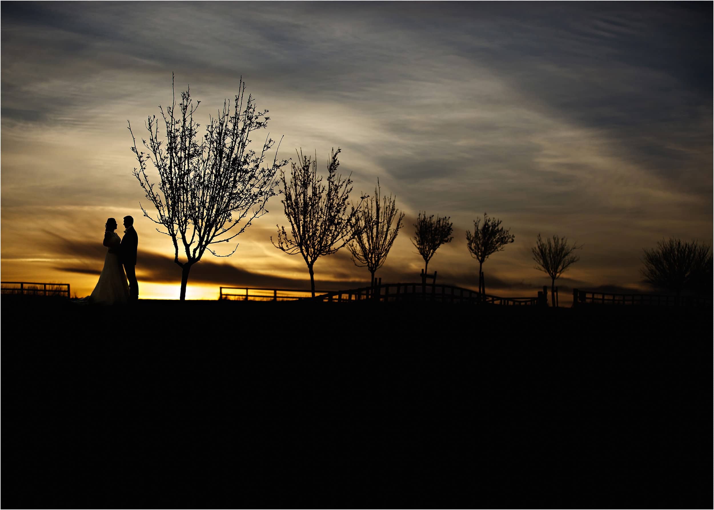 a silhouette of the bride and groom at sunset