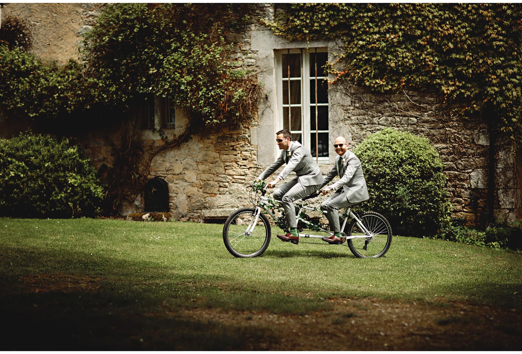 the groom & best man arriving on a tandem bicycle