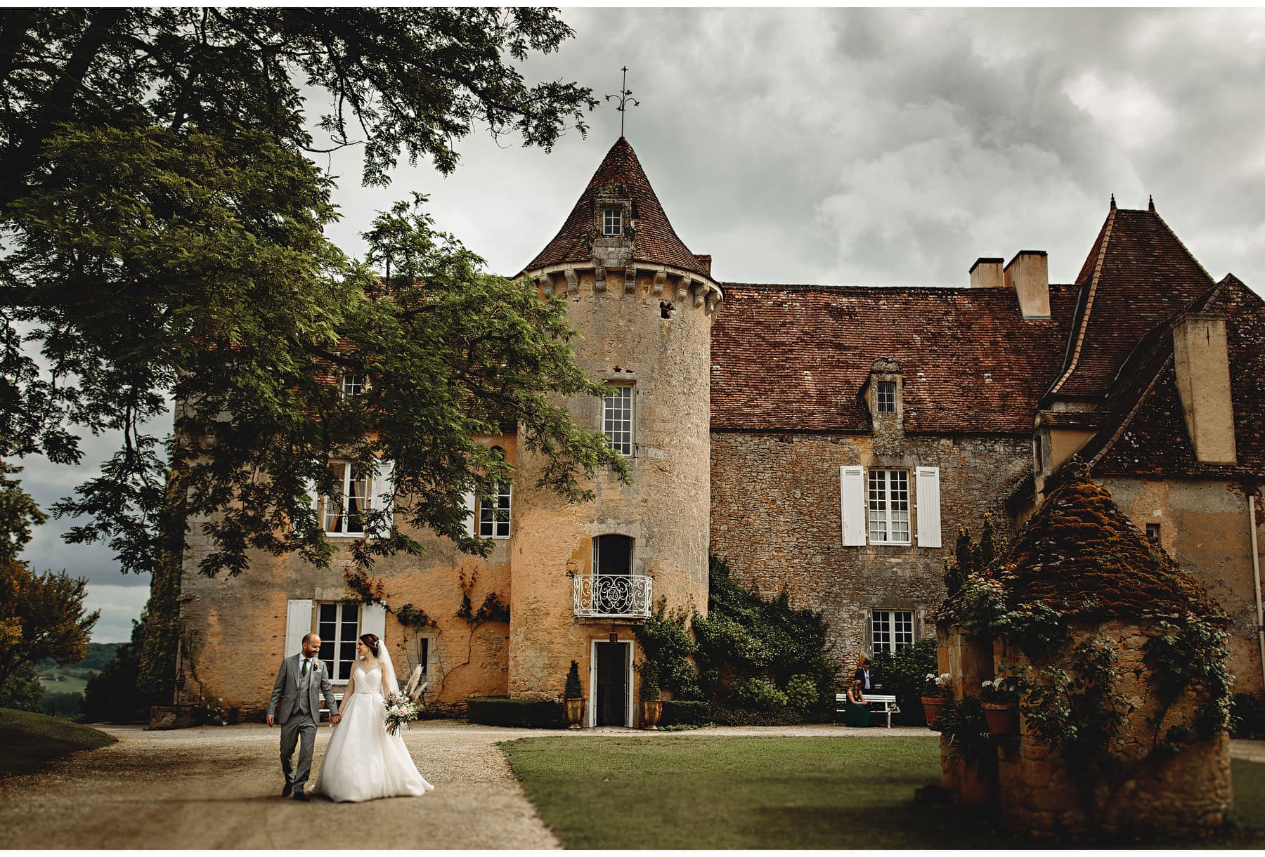 the bride & groom walking with Château Cazenac in the background