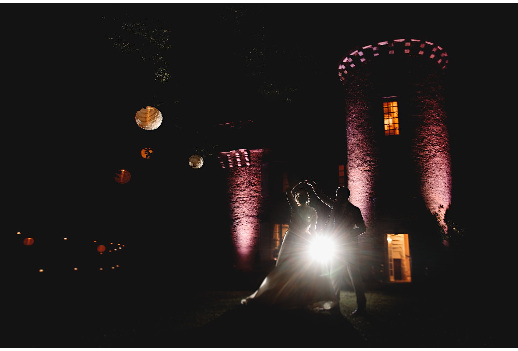 the bride & groom dancing outside with the building lit up