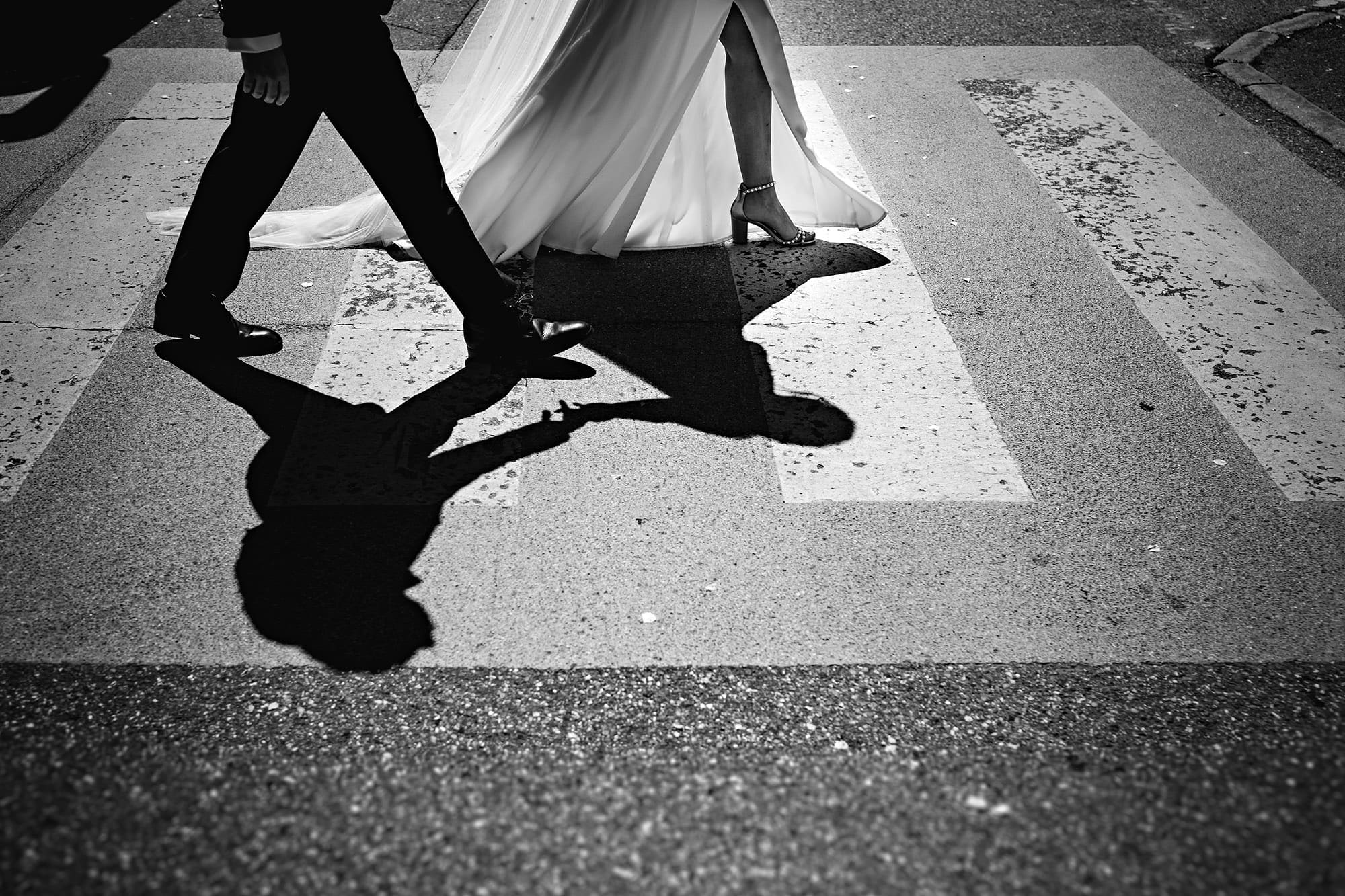 A bride and groom crossing a street in Annecy captured by a wedding photographer.