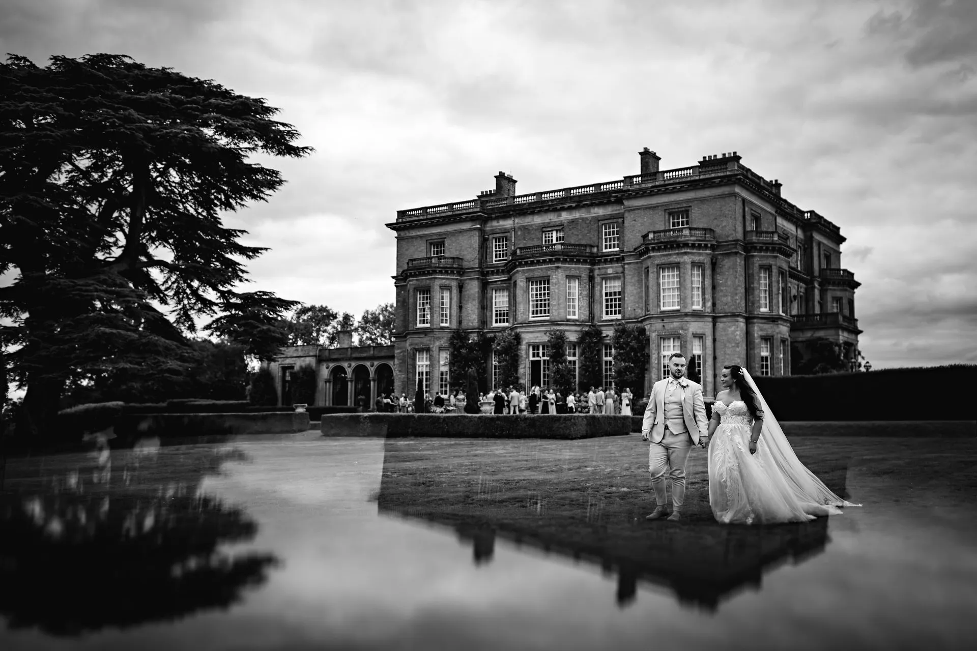 A black-and-white photo showing the bride and groom walking away from head to house on their wedding day