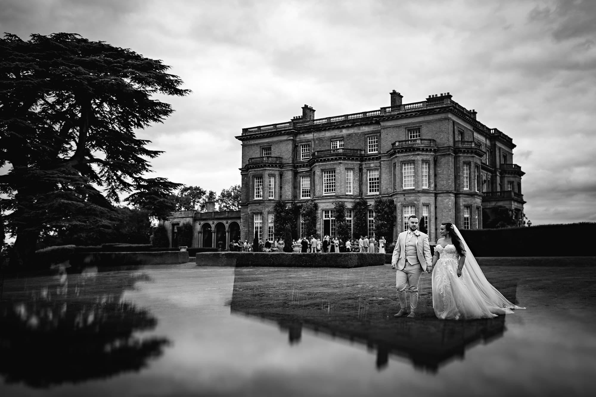 A wedding couple posing at Hedsor House as they walk away from their wedding reception party for photos